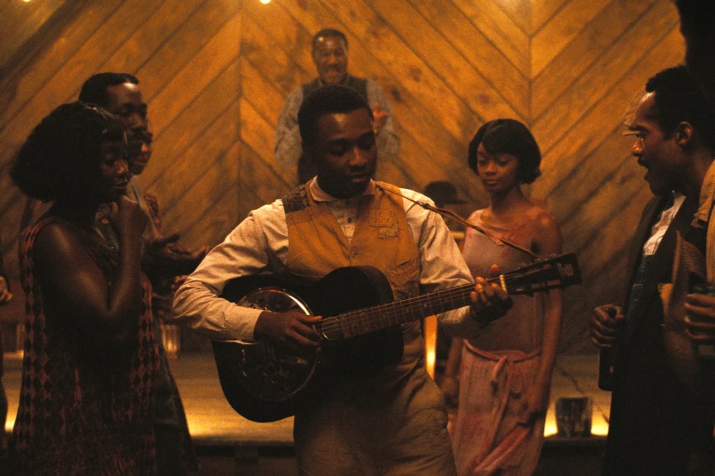 Sammie playing the guitar at a juke joint in a scene from the movie "Sinners."